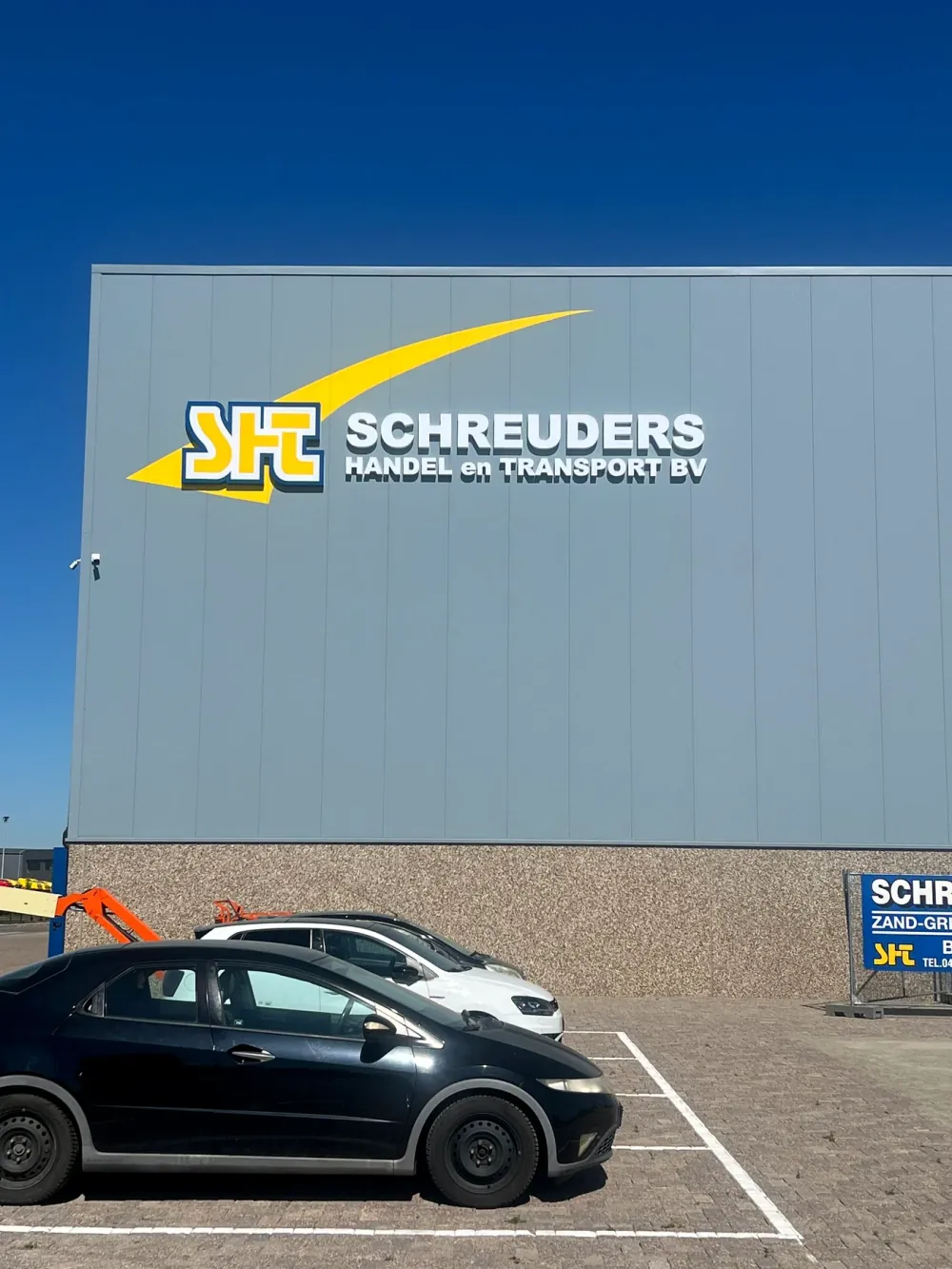 Grote gevellichtreclame voor Schreuders Handel en Transport bij daglicht